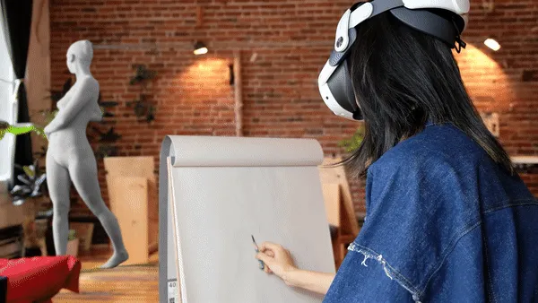 An artist drawing at an easel while wearing a VR headset